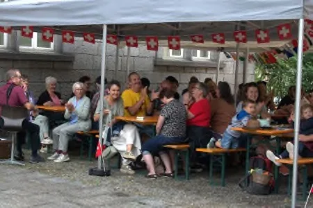 Abitanti a colazione sotto un tendone con bandierine svizzere